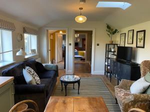 a living room with a couch and a table at The Old Piggery - tranquil garden guest cottage in Hail Weston