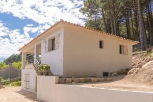 a small white house on top of a hill at Entre mer et montagne Villa Cartalavonu in Porto-Vecchio