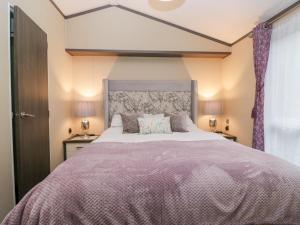 a bedroom with a large bed with purple sheets at Feather Hill Lodge White Cross Bay, Skiptory Howe 38 in Windermere