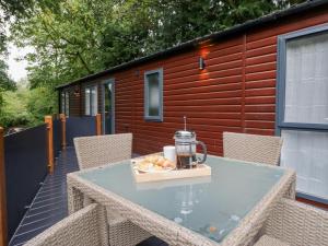 a glass table with a drink and a plate of food on a patio at Feather Hill Lodge White Cross Bay, Skiptory Howe 38 in Windermere