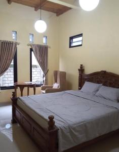 a bedroom with a bed and a chair and windows at Villa Omah Singgah Gunung Andong in Magelang