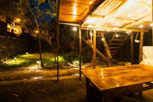 a tent with a wooden table in a yard at night at Pinkuylluna Lodge in Ollantaytambo +4 photos