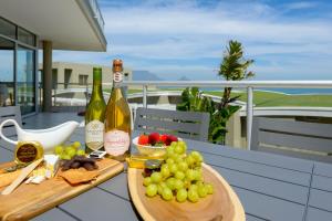 a table with two bottles of wine and a bowl of grapes at Dolphin beach Apartment -Kite beach in Cape Town