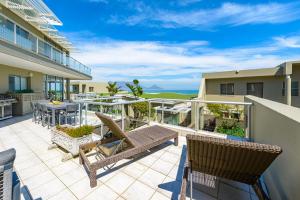 a patio with chairs and tables on a balcony at Dolphin beach Apartment -Kite beach in Cape Town