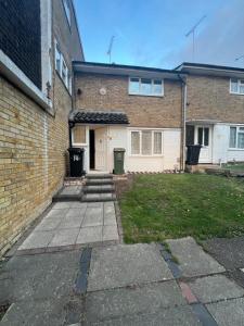 ein Backsteinhaus mit einer weißen Tür und einem Hof in der Unterkunft 3 Bed Home, Sleeps 7 with Garden in Basildon in Basildon