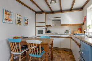 a kitchen with a wooden table and blue chairs at No 1 Cottage in Brixham