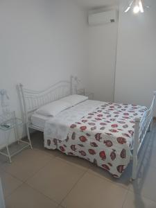 un lit blanc avec un couvre-lit avec des roses dessus dans l'établissement Tamarin De Mar, à Alghero