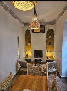 マラケシュにあるRiad Awel Oasis Privée au coeur de la Medinaのリビングルーム(テーブル、椅子、照明付)