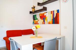 a white dining room table with chairs and a vase with flowers at La casa di Leonardo in Civitanova Marche