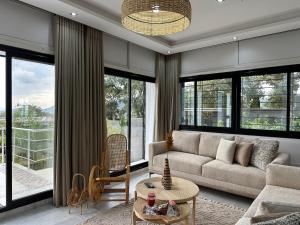 a living room with a couch and large windows at Maison Lés - Ain Drahem in Ain Draham