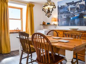 une salle à manger avec une table et des chaises en bois dans l'établissement Needle Cottage, à Cullen