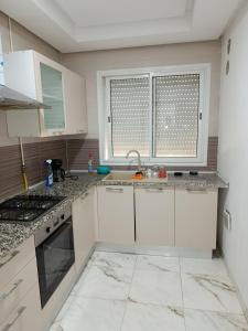 une cuisine avec des armoires blanches, un évier et une fenêtre dans l'établissement Mira house, à Ariana 2 autres photos