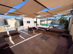 un patio con un sofá bajo una sombrilla en Nay's Chalet, en Shūnat Nimrīn