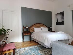 a bedroom with a large white bed and a couch at Guinea Fowl Lodge - Lagoon & Heads View B&B, Central Knysna in Knysna