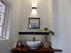 a bathroom with a sink and a potted plant at Guinea Fowl Lodge - Lagoon & Heads View B&B, Central Knysna in Knysna