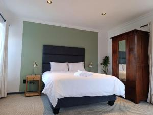 a bedroom with a large white bed and a mirror at Guinea Fowl Lodge - Lagoon & Heads View B&B, Central Knysna in Knysna