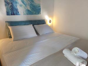 a bed with white sheets and pillows in a room at To kamnaki seaview in Mykonos' heart in Mýkonos City