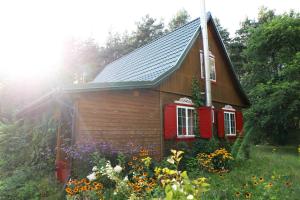 a small house with a red window and flowers at Chata Wiedźmy - Sanktuarium Laparica w Puszczy Białej 