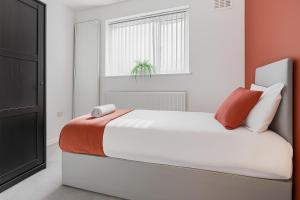 a bedroom with a white bed with orange and white pillows at Highland House in Birmingham +11 photos