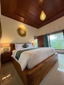 a bedroom with a large bed with a wooden headboard at D'Labake Guest House in Sidemen