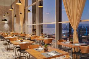 a restaurant with tables and chairs and large windows at NH Iquique Pacifico in Iquique +43 photos
