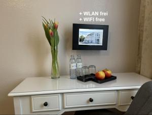 a table with a vase of flowers and bottles on it at Müller Apartments zur S-Bahn Oberschleißheim in Oberschleißheim +3 photos