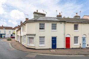 ein weißes Haus mit roten und blauen Türen in einer Straße in der Unterkunft The Old Shoe Shop, 5 Well Lane in Clare
