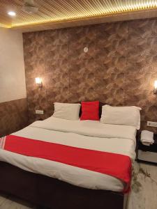 a bedroom with a large bed with a red pillow at Hotel Metro Residency Kalkaji in New Delhi