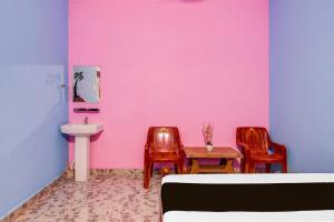 a pink room with two chairs and a table and a sink at Hotel O Gurukrupa in Urāli +21 photos