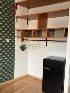 a kitchen with a black refrigerator and shelves at Chez Nathou in Janzé