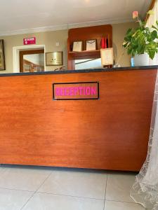 un mostrador de recepción con un cartel de registro rojo. en Casa MaSa Inn, en Francistown