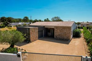 ein Haus mit einer Garage und einem Zaun in der Unterkunft luxury villa les Kiks 5 chambres, piscine chauffée, Lecci in Lecci