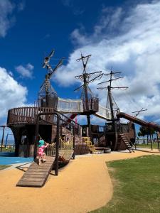 a child standing in front of a pirate ship playground at アラハブルーリゾート in Chatan