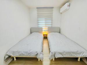 two beds in a small room with a window at 후암가옥 in Seoul