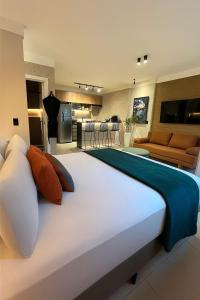 Cama grande en habitación con sala de estar en Flat Praia Comfort Camburi, en Vitória
