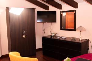 1 dormitorio con tocador y TV en la pared en Villa Forzisi locazioni brevi, en Fiumefreddo di Sicilia