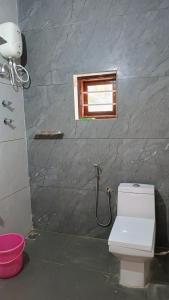 a bathroom with a white toilet and a window at Nagesh paikera biligeri in Madikeri
