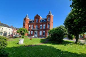 a large red brick building on a green yard at Le petit Château Avesnois - Studio avec terrasse vue sur le jardin in Avesnes-sur-Helpe