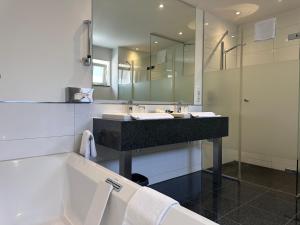 ein Badezimmer mit Waschbecken, Badewanne und Spiegel in der Unterkunft Schlosshotel Ahaus in Ahaus + 35 Fotos