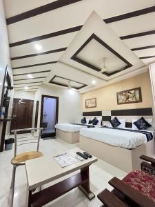 a room with two beds and a table and a chair at Hotel Siddhi Vinayak in Jodhpur