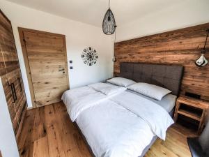 a bedroom with a large bed with a wooden wall at Zeitfrei Chalet Apartments in Fieberbrunn