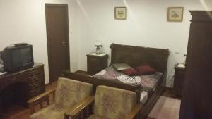 - une chambre avec un lit, deux chaises et une télévision dans l'établissement Casa Boavista, à Paredes de Coura