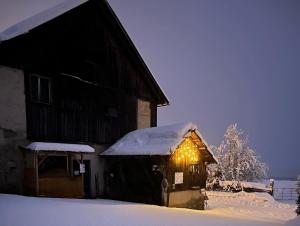 a barn covered in snow with lights on it at Pferdehof Rupitsch - Haus Carina in Weissensee +6 photos