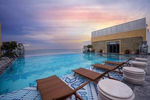 una grande piscina con sedie e l'oceano di Khách sạn Apec Mandala Tuy Hoà Phú Yên New a Tuy Hoa