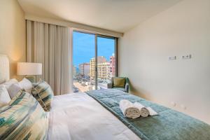 a bedroom with a bed and a large window at Cond Bayline - Safia - Pool - SPA - Beach - GYM - BY BEDZY in Armação de Pêra +30 photos