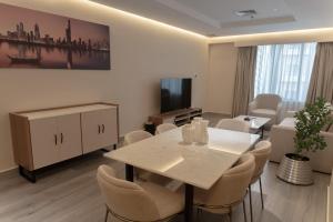 a living room with a table and chairs and a tv at Sara Plaza in Kuwait