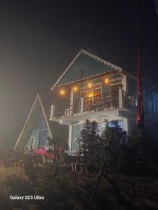a white house with a balcony at night at Dara Homestay, Charkhole in Kalimpong