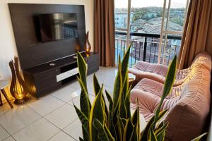 Una sala de estar con televisión y una planta en Vista do pôr de sol, 5 min a pé da praia Tartarugas, 3 supermercados e igreja universal, super arejado, en Rio das Ostras 17 fotos más