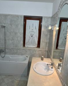 Un baño con lavabo, bañera y espejo. en House in Cave, en Massafra
