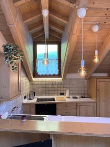 a kitchen with wooden ceilings and a sink and a window at Mansarda Ai Tigli in Castello di Fiemme